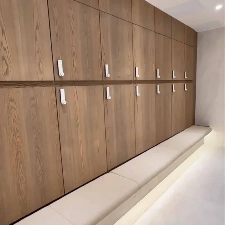 Modern hotel locker room with wooden lockers, soft bench seating, and warm lighting, offering comfort and convenience.