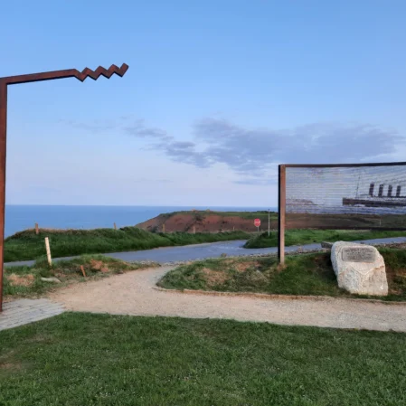 Scenic coastal path with Titanic memorial, lush greenery, and ocean view near a charming hotel retreat.