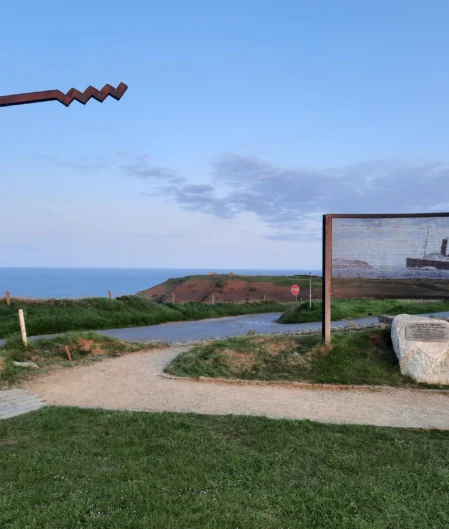 Scenic coastal path with Titanic memorial, lush greenery, and ocean view near a charming hotel retreat.