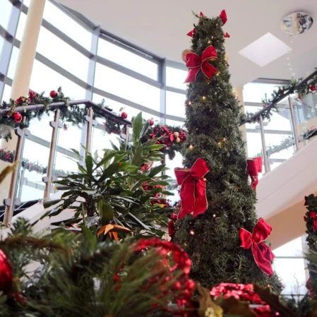 Elegant spiral staircase adorned with festive Christmas decorations and lush greenery in luxurious hotel lobby.