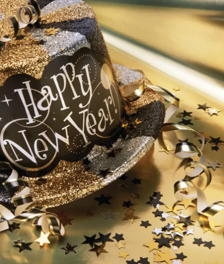 Festive New Year’s Eve hat with gold and silver decorations on a golden surface, perfect for celebratory hotel events.
