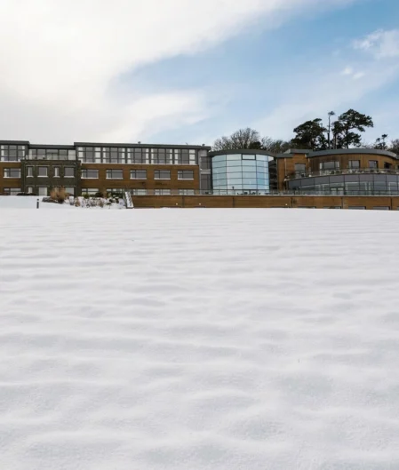 Luxurious hotel with modern architecture set against a snowy landscape under a clear blue sky. Perfect winter retreat.