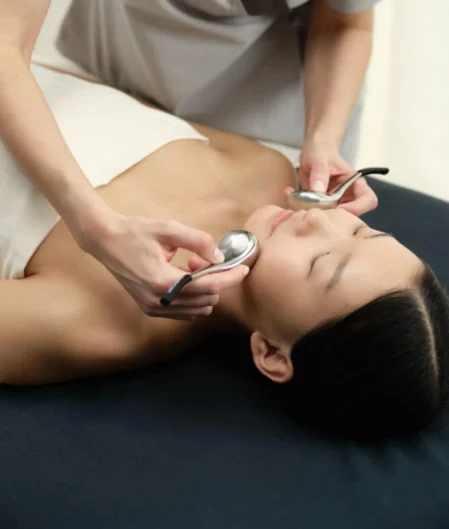 Guest enjoying a soothing facial treatment at luxury spa, featuring plush massage table and calming ambience.
