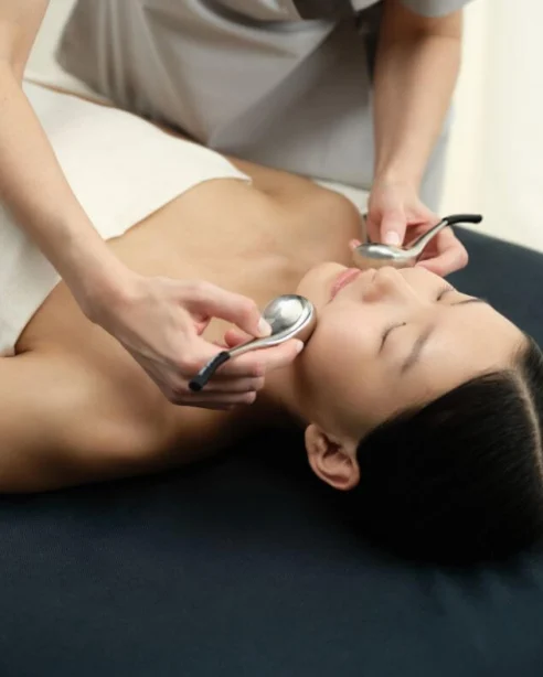 Guest enjoying a soothing facial treatment at luxury spa, featuring plush massage table and calming ambience.