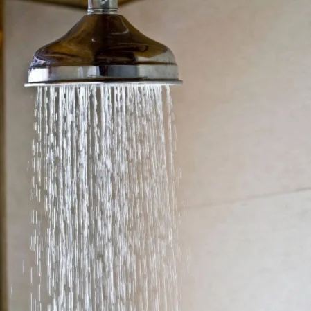 Elegant rainfall shower head in modern hotel bathroom, offering a relaxing, luxurious experience for guests.