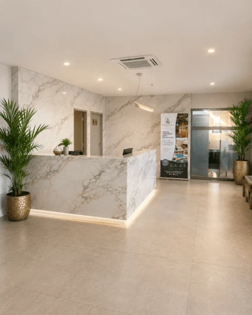 Elegant hotel reception with marble desk, lush plants, warm lighting; inviting atmosphere for your stay.