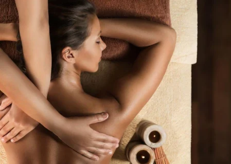 Relaxing massage at luxury hotel spa with candles and plush, warm setting.
