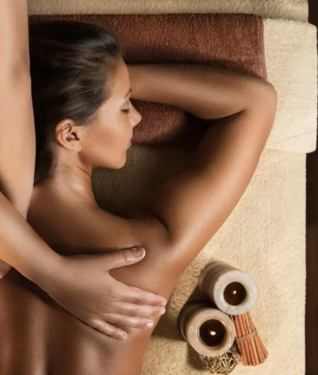 Relaxing massage at luxury hotel spa with candles and plush, warm setting.