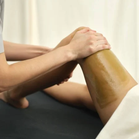 Relaxing spa massage on client's leg in serene setting.
