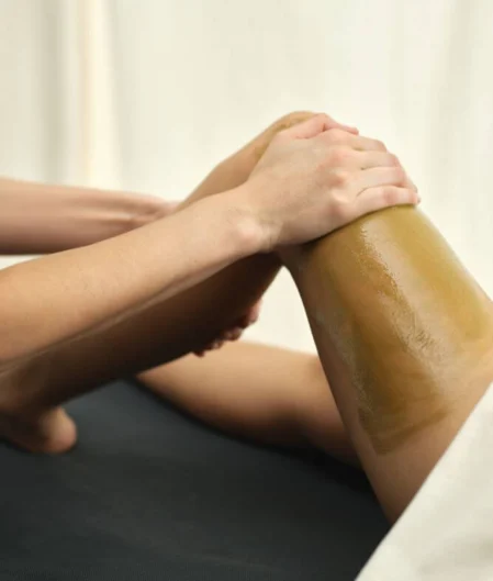 Relaxing spa massage on client's leg in serene setting.