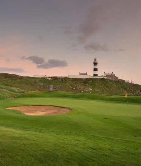 Scenic golf course with coastal views, featuring a historic lighthouse at sunset, perfect for a relaxing stay.